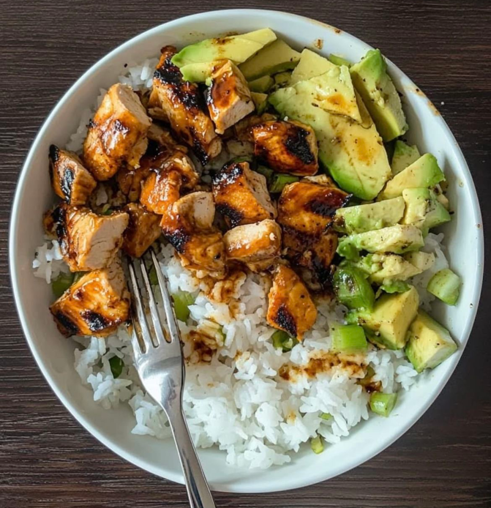 A bowl with white rice, chicken and avacado